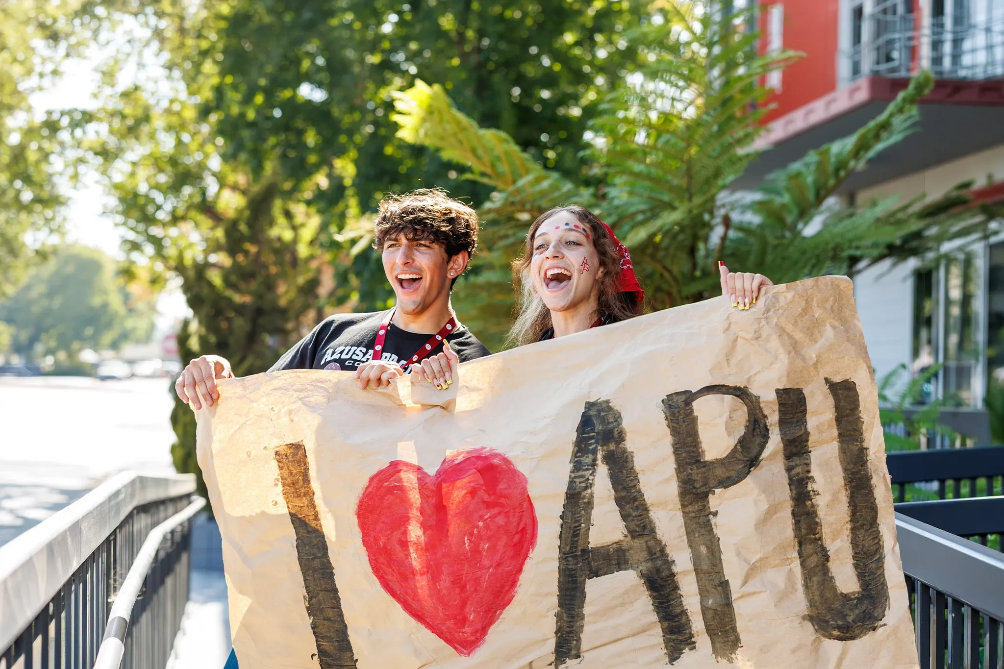 Two students holding an I Heart APU sign