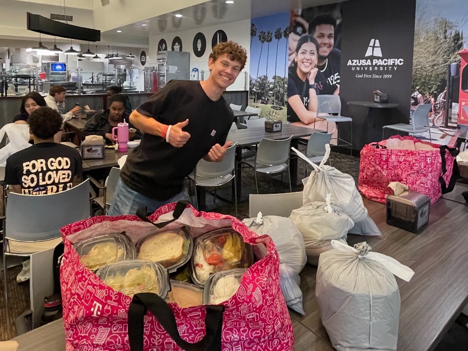 Aaron Lakeman stands in the dining hall with packed to-go boxes to hand out.
