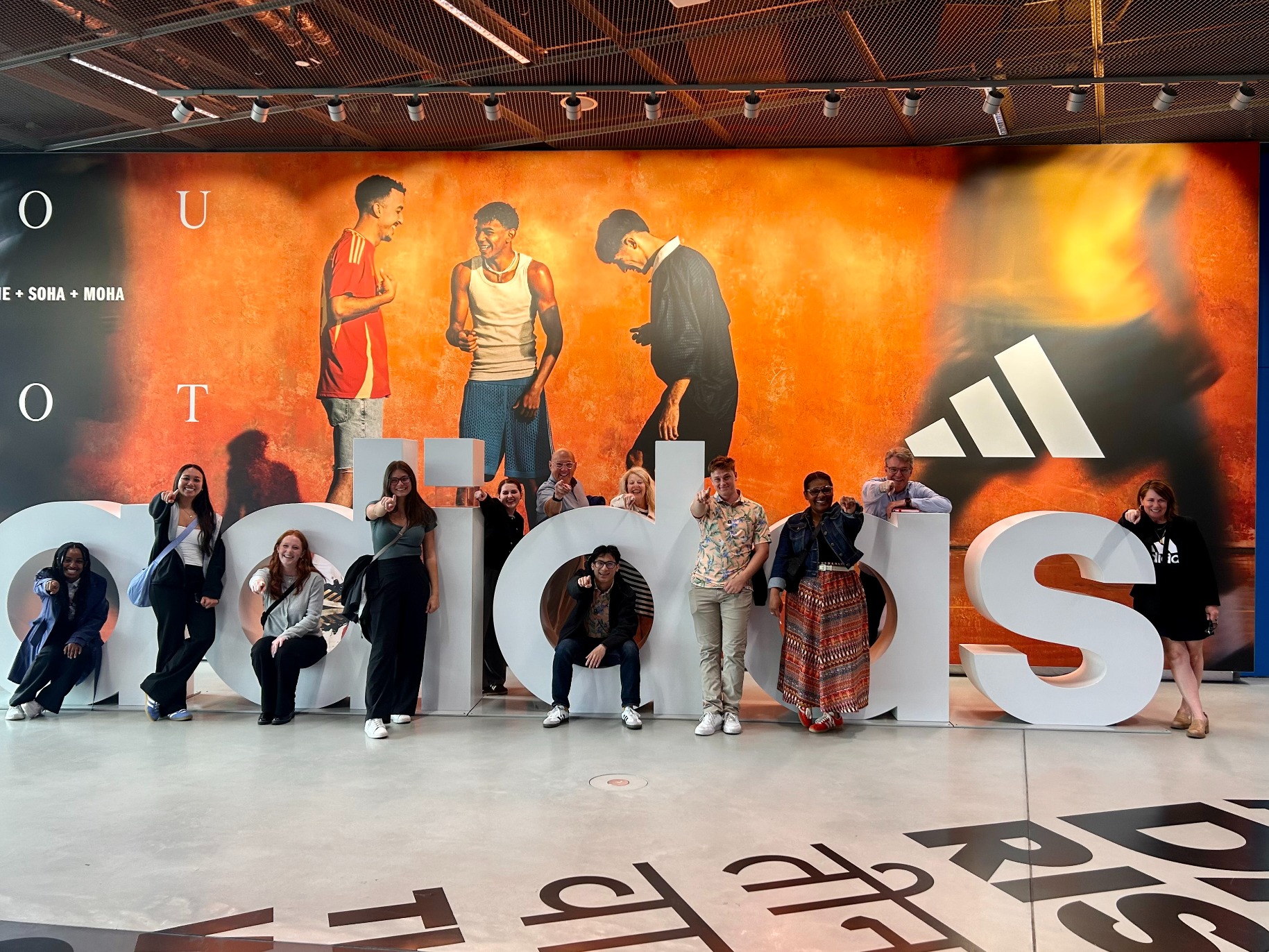 Students pose in front of an Adidas sign