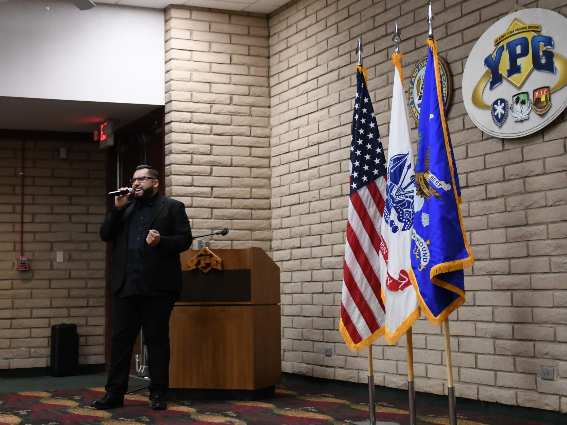 Carlos holding a mic with flags in the background