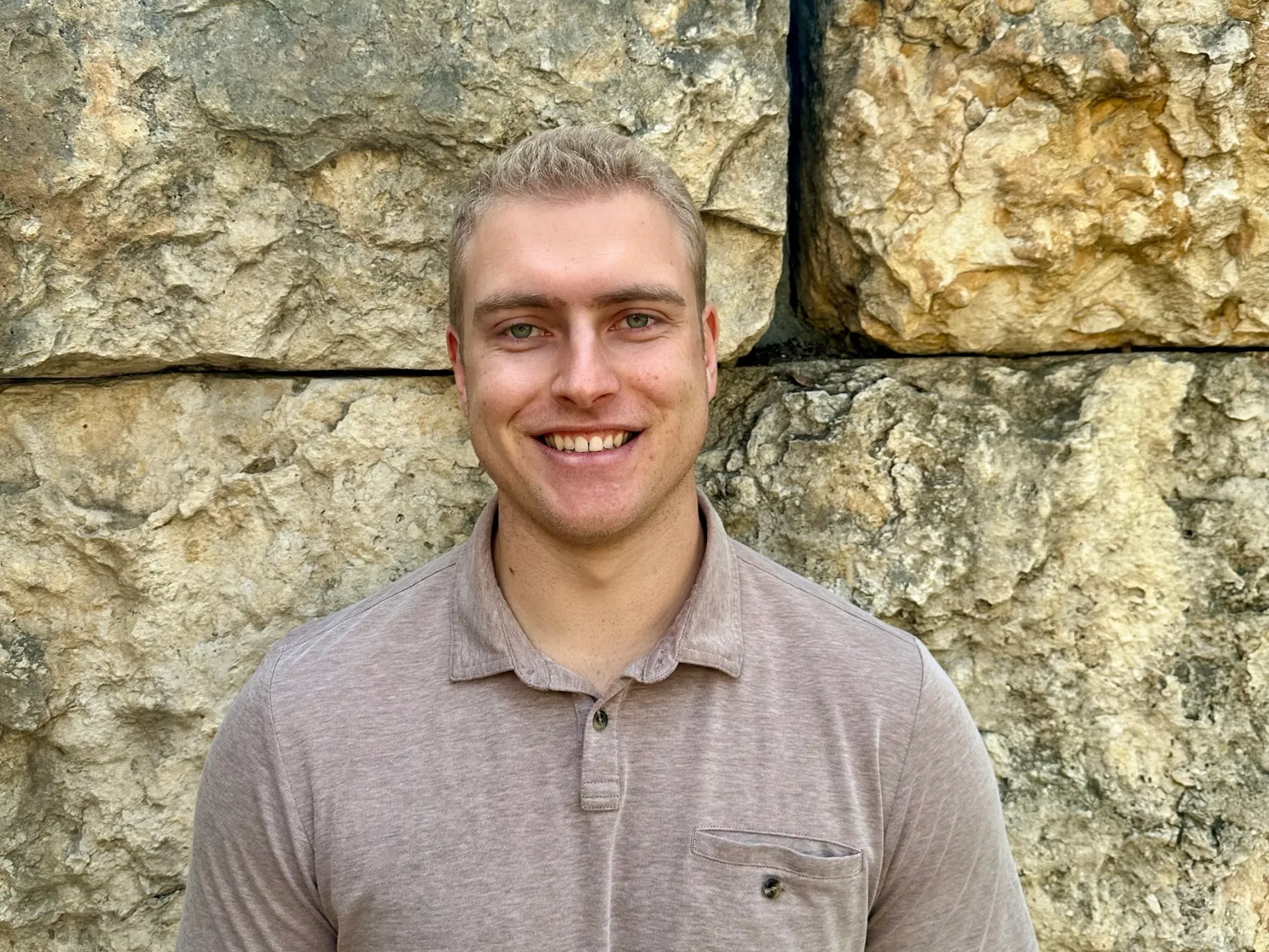 Matthew Lanzone smiles in front of APU's prayer wall.