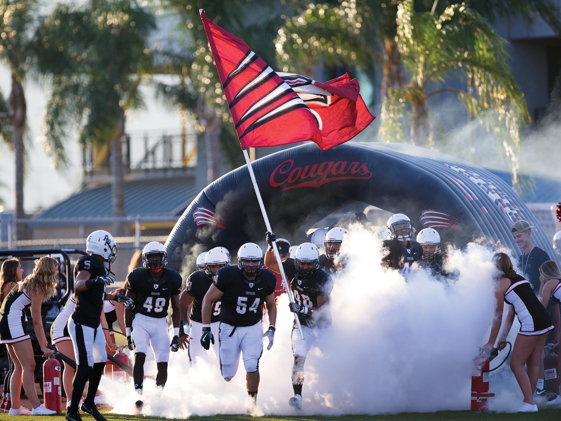 APU football players rush out of a tunnel before a game