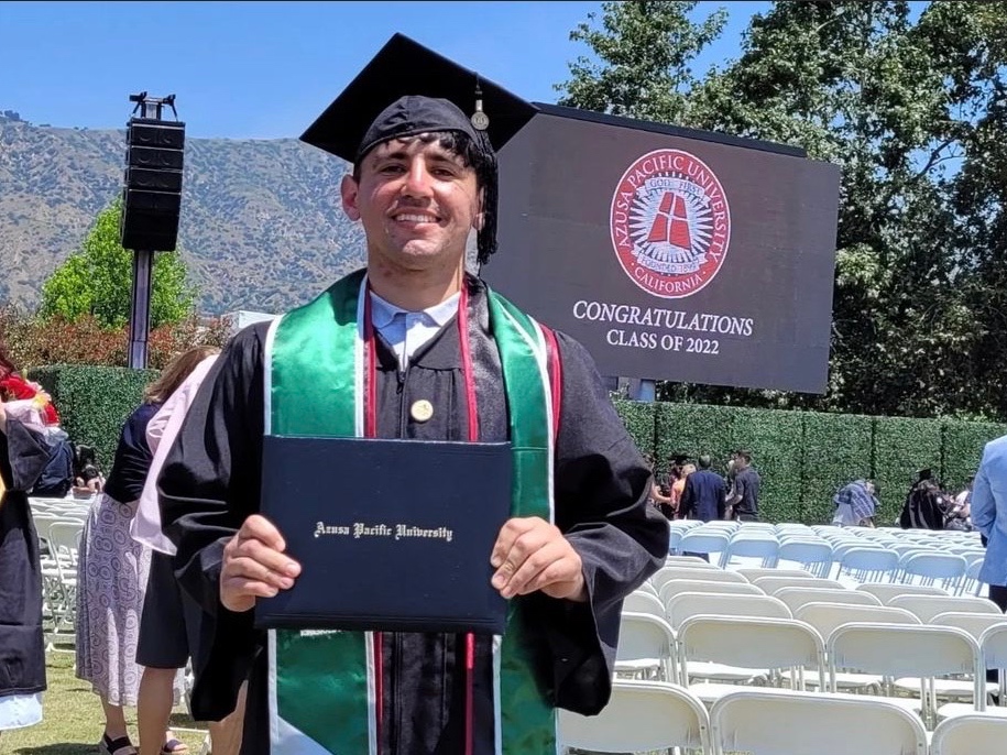 Rolando Robles proudly holds his degree at commencement.