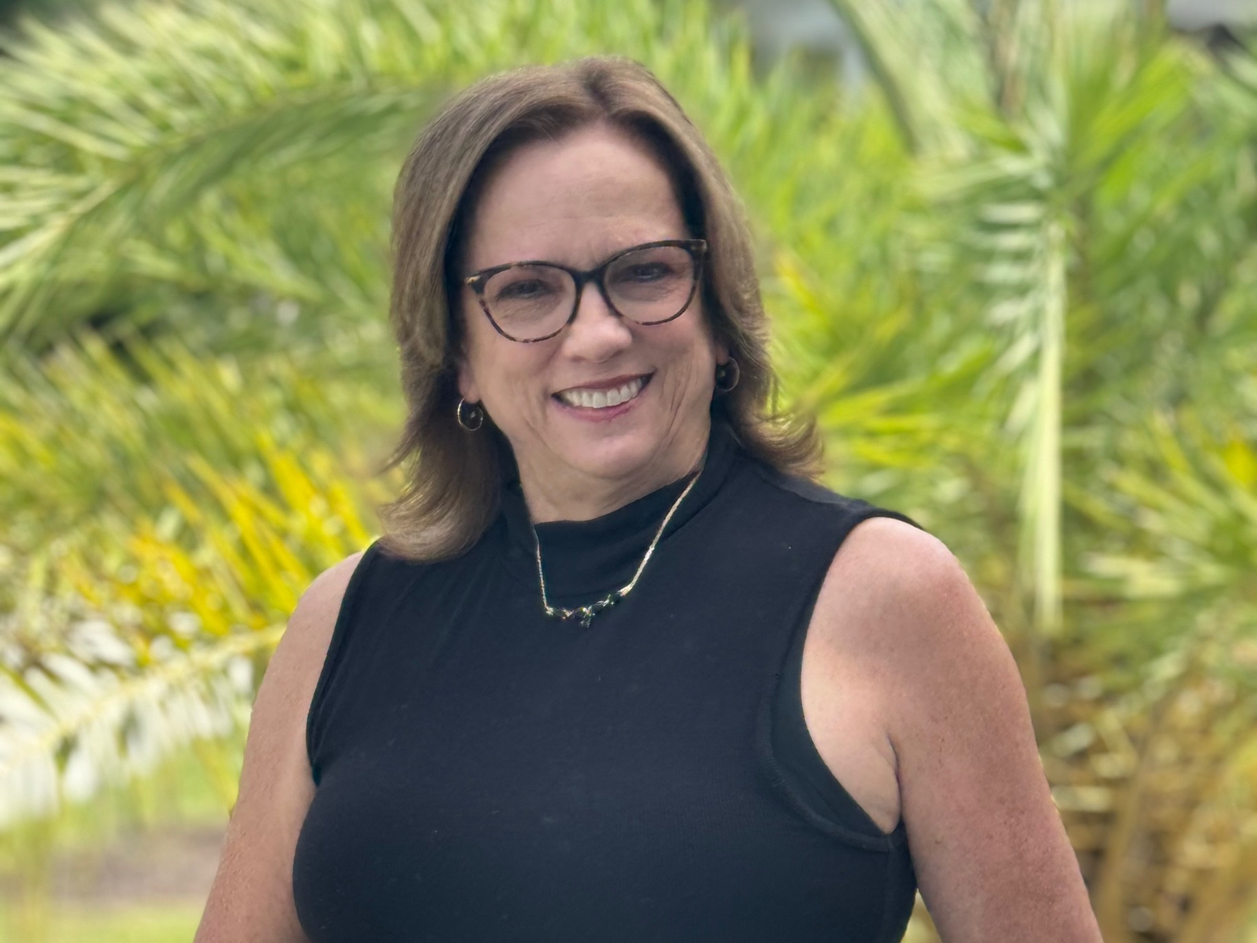 sharon smiles in front of palm trees