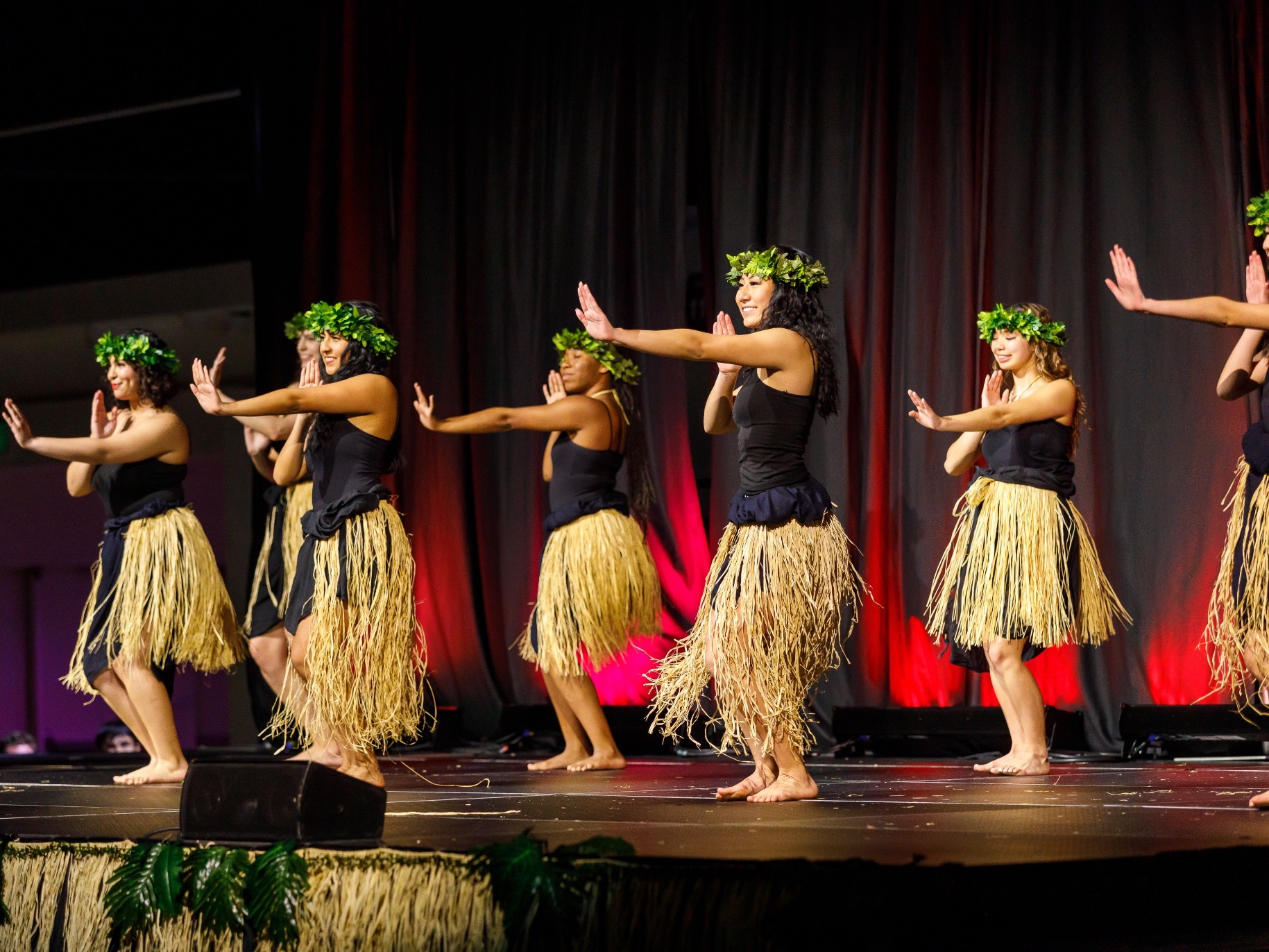 female students hula dance on stage at APU's annual luau