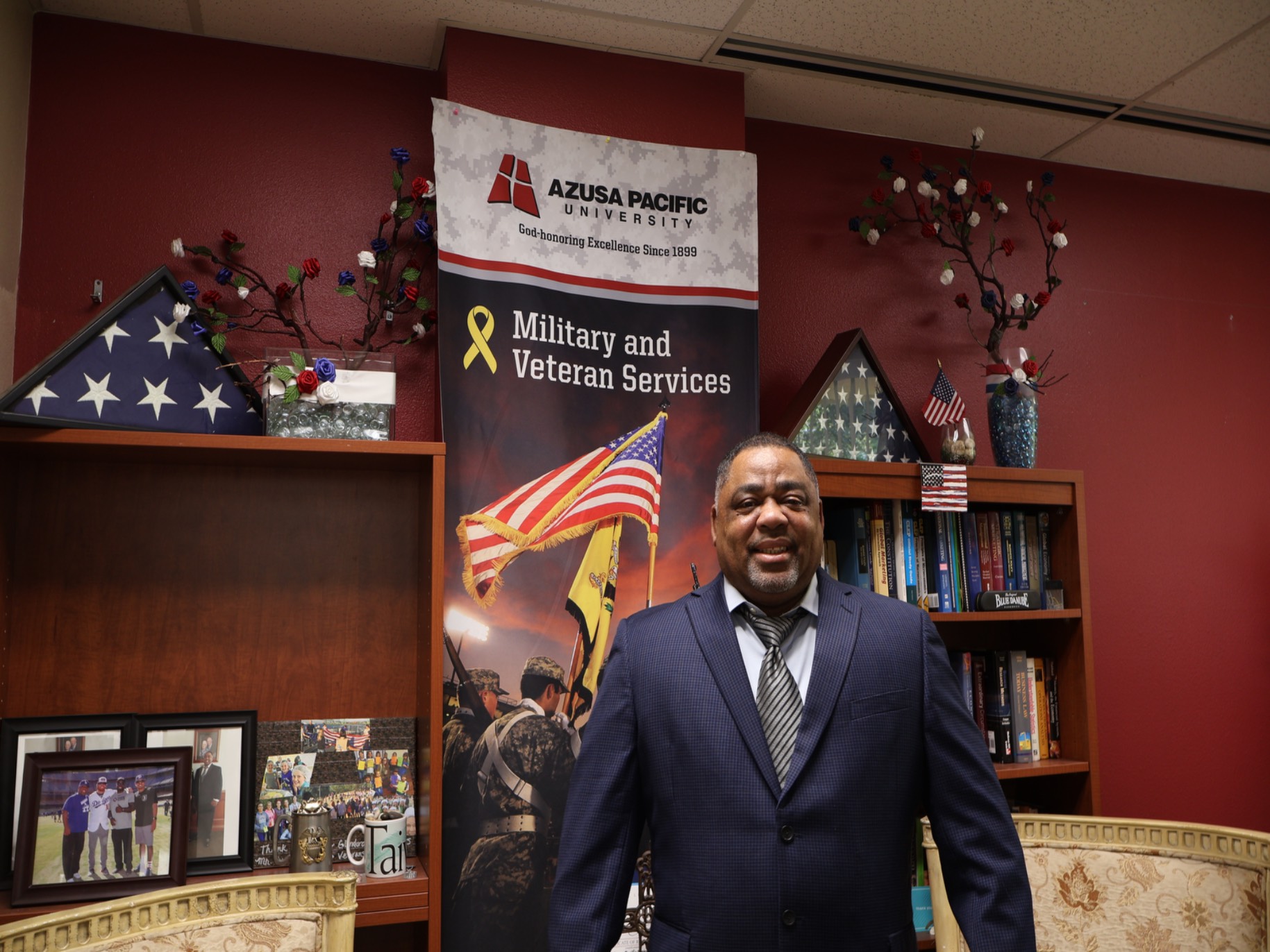 Everette smiles in his office, full of American flags and many books.