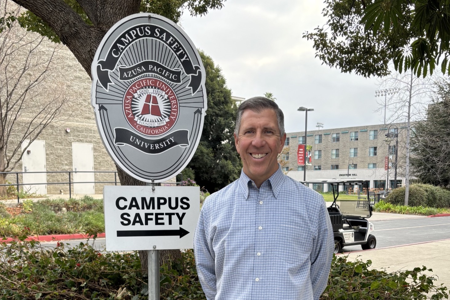 John smiles outside the campus safety office, near the dorms