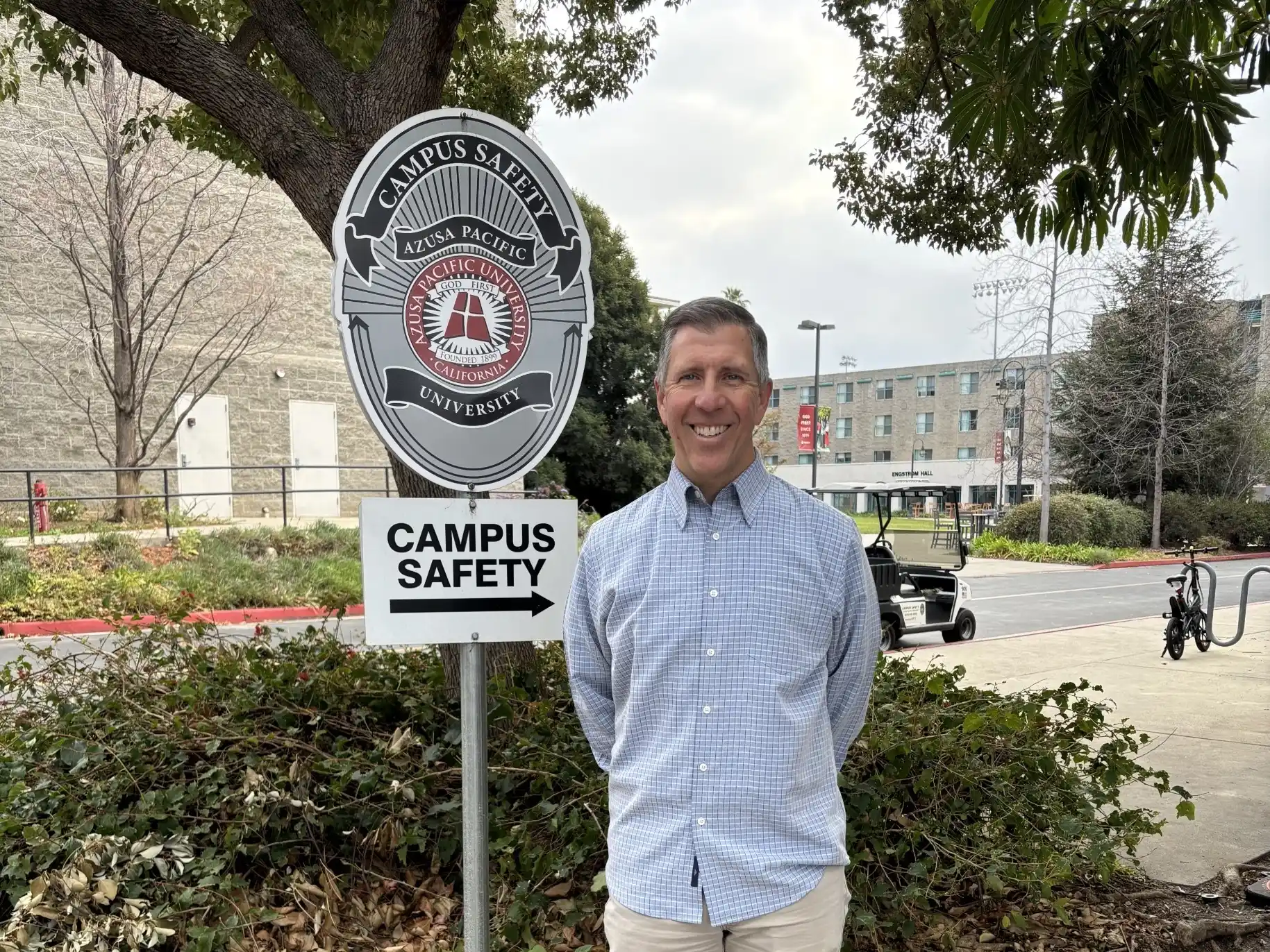 John smiles outside the campus safety office, near the dorms