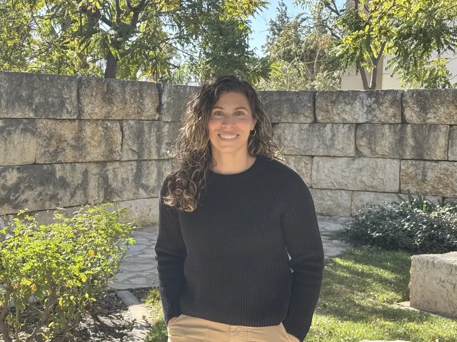 Leslie smiles outside the prayer garden on west campus on a sunny day.