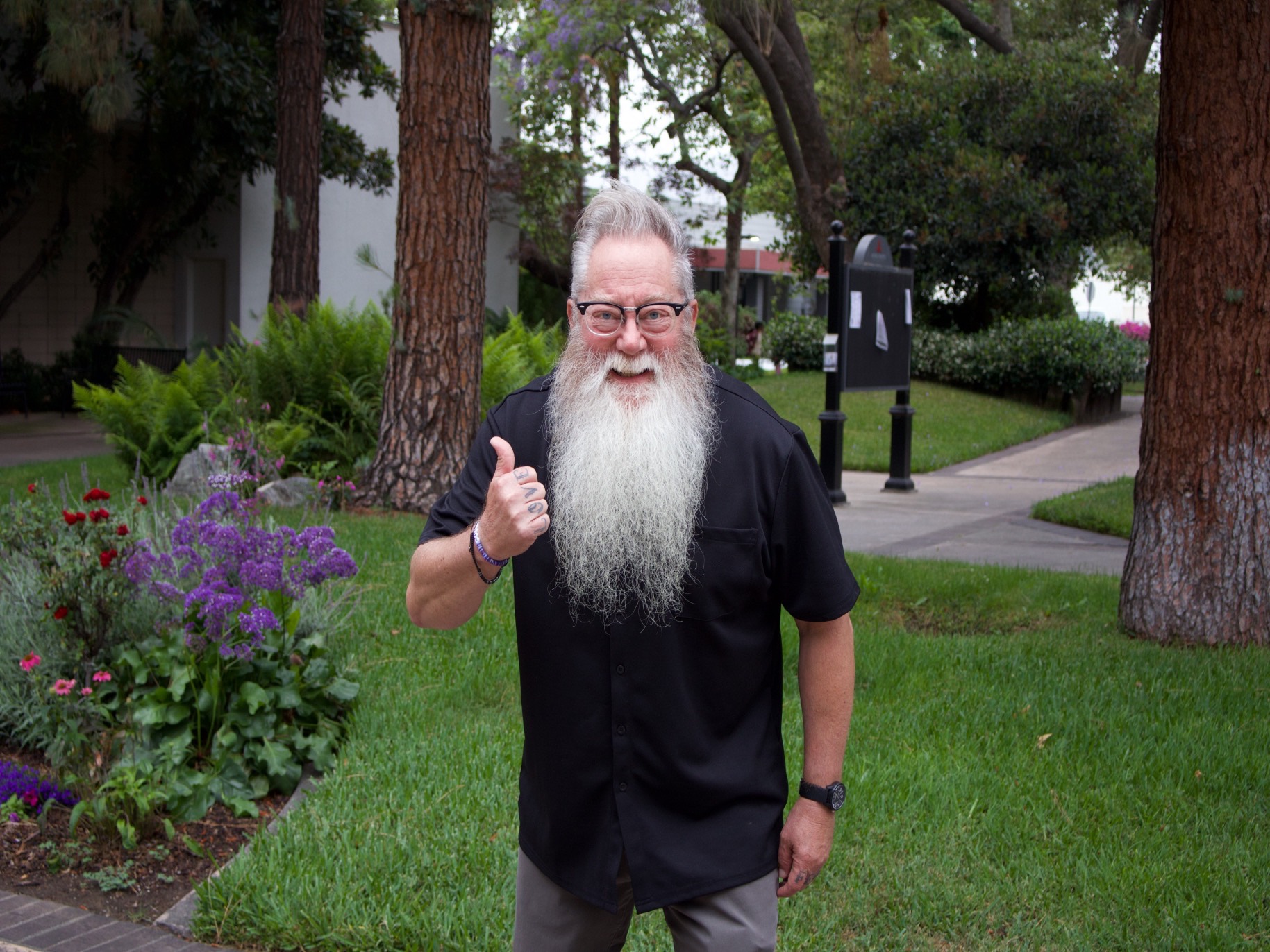 Matt smiles with a thumbs up outside east campus