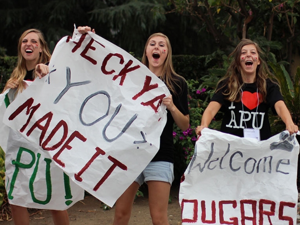 students on campus holding welcome weekend signs