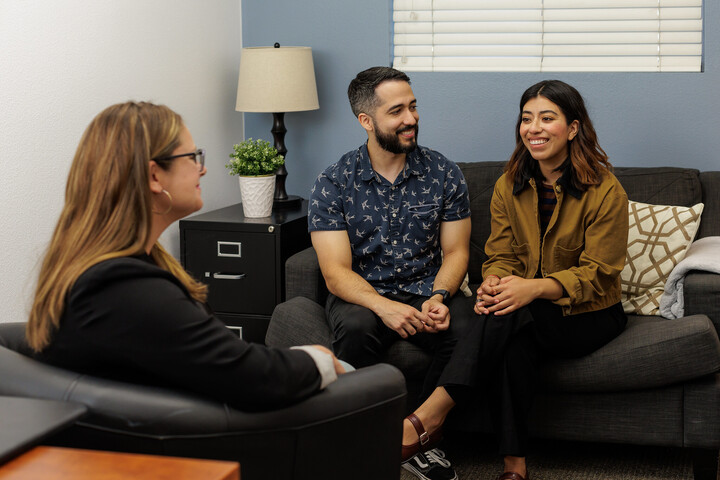 Two people sit on couch with therapist sitting in chair opposite