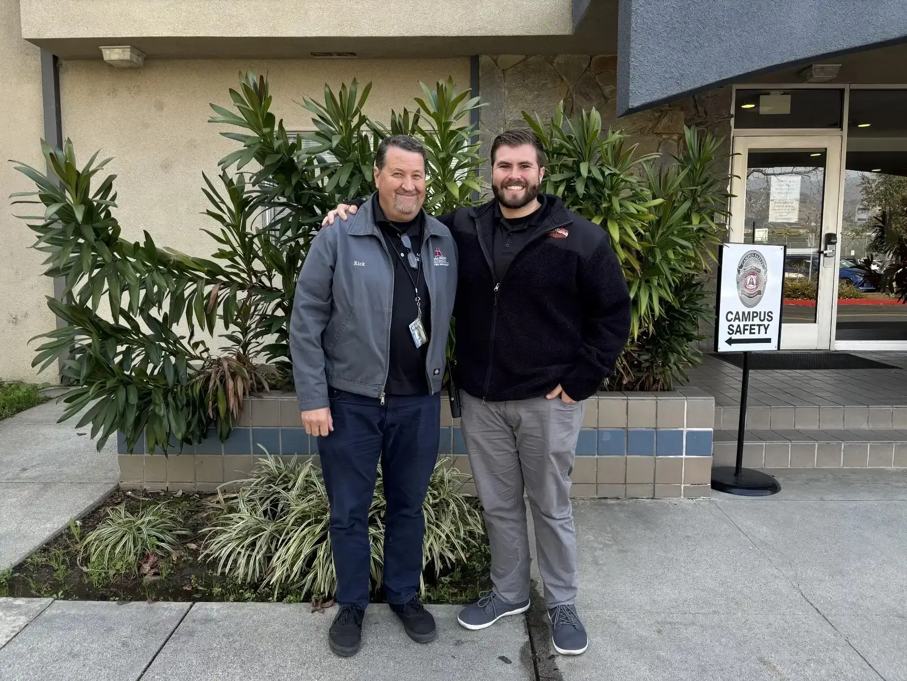 Rick and Richie Orr, father and son, smile outside the campus safety office, Richie's arm around his father