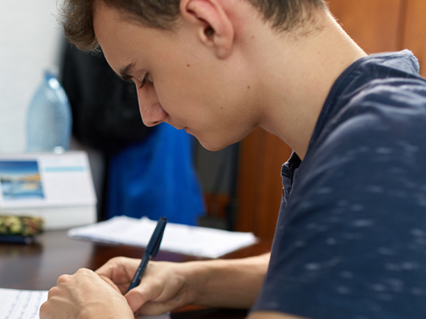 student wearing and writing on a book