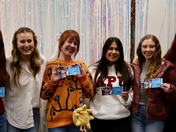 students smiling and holding taylor swift tickets