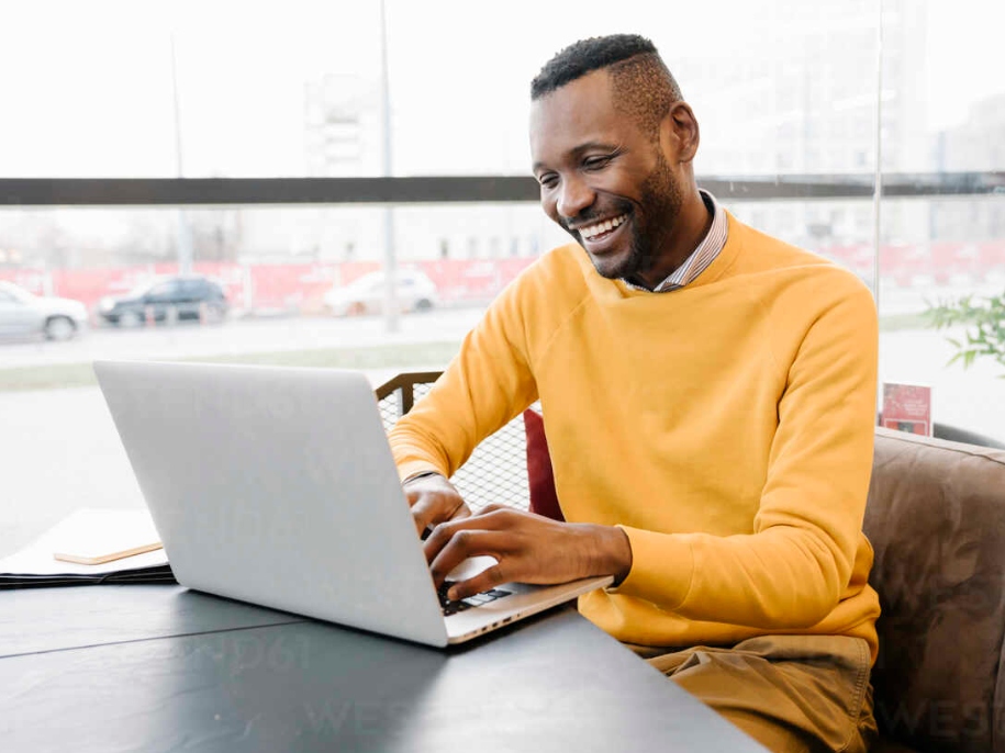 man wearing yellow and using his laptop