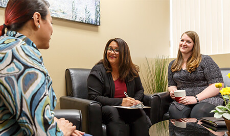 3 people facing each other on sofas, speaking