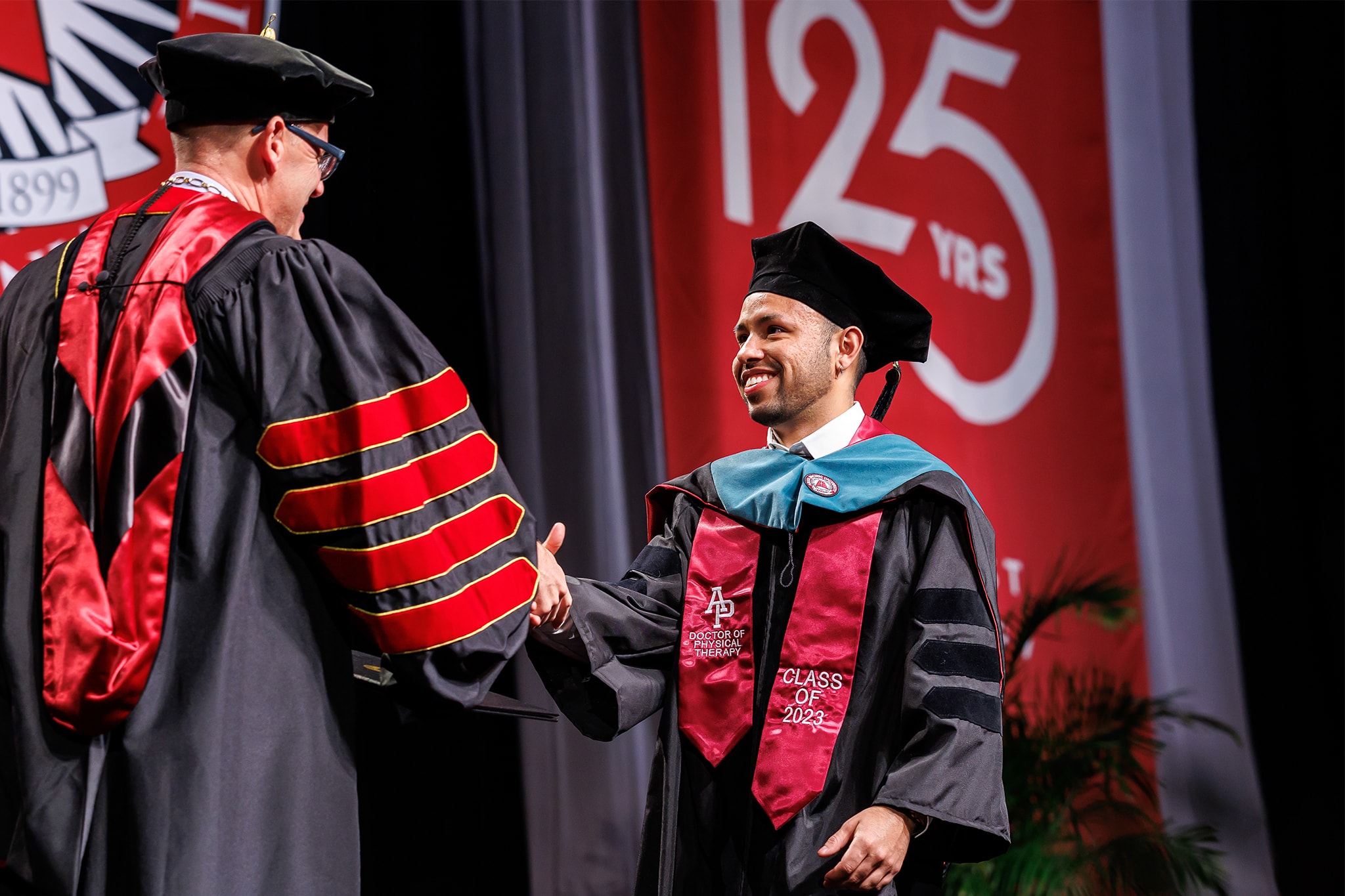 Student shaking hands with President Adam at commencement