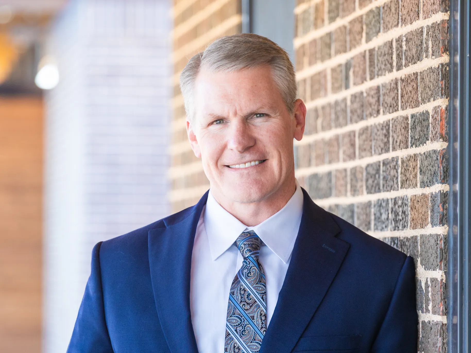 Dale Meinecke smiles in front of a building