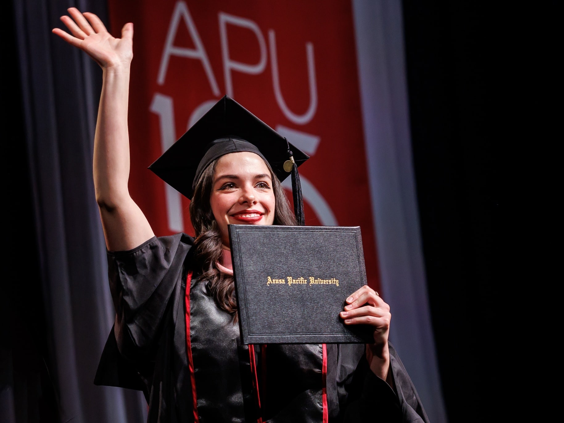 A graduate walks across the commencement stage holding her diploma