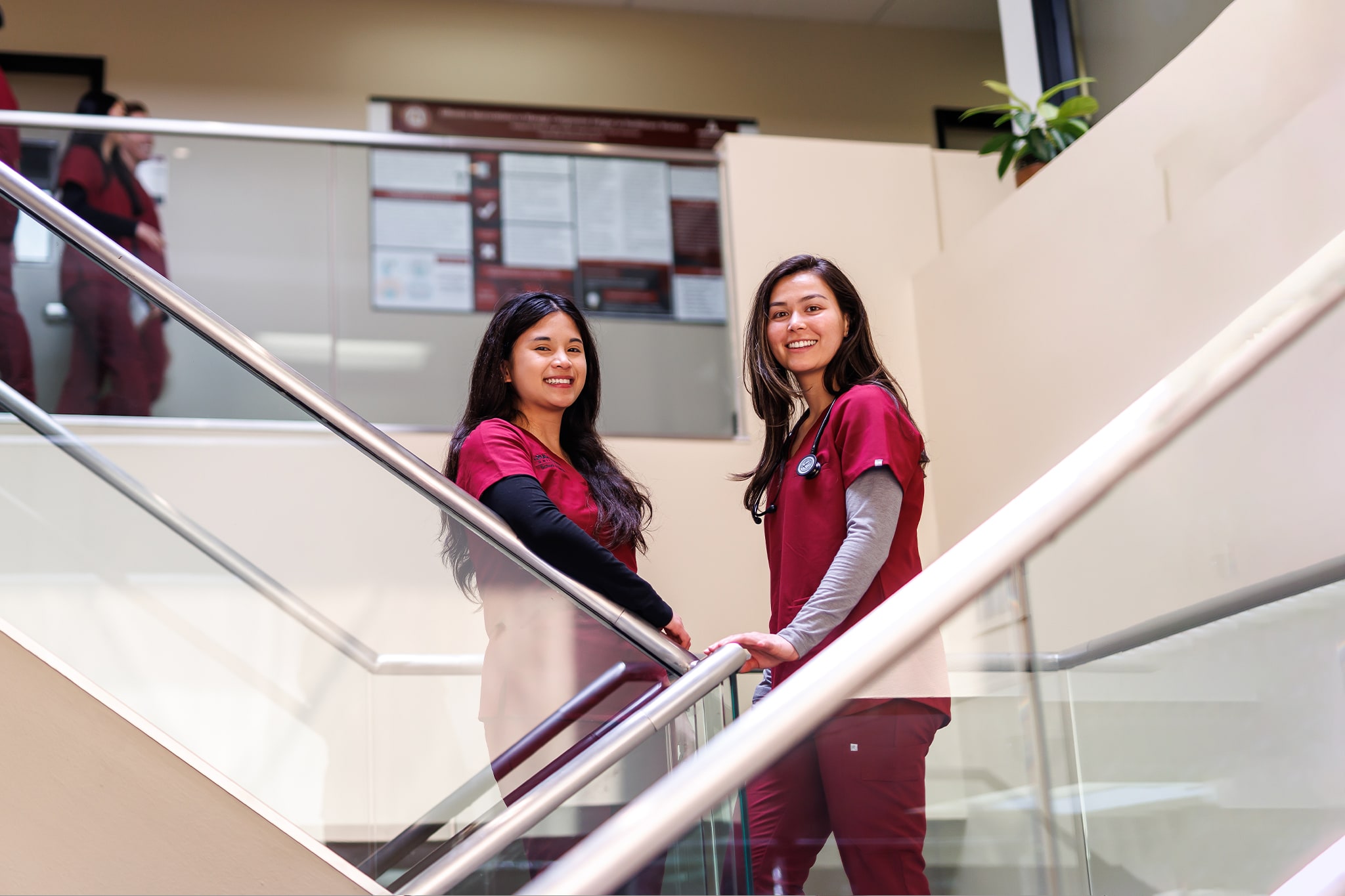 Two nursing students smiling from a set of stairs