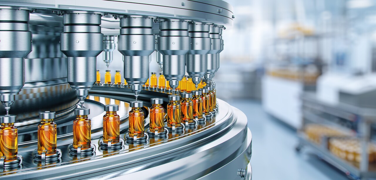 Manufacturing machine with multiple nozzles filling small glass bottles with amber-colored liquid substances.