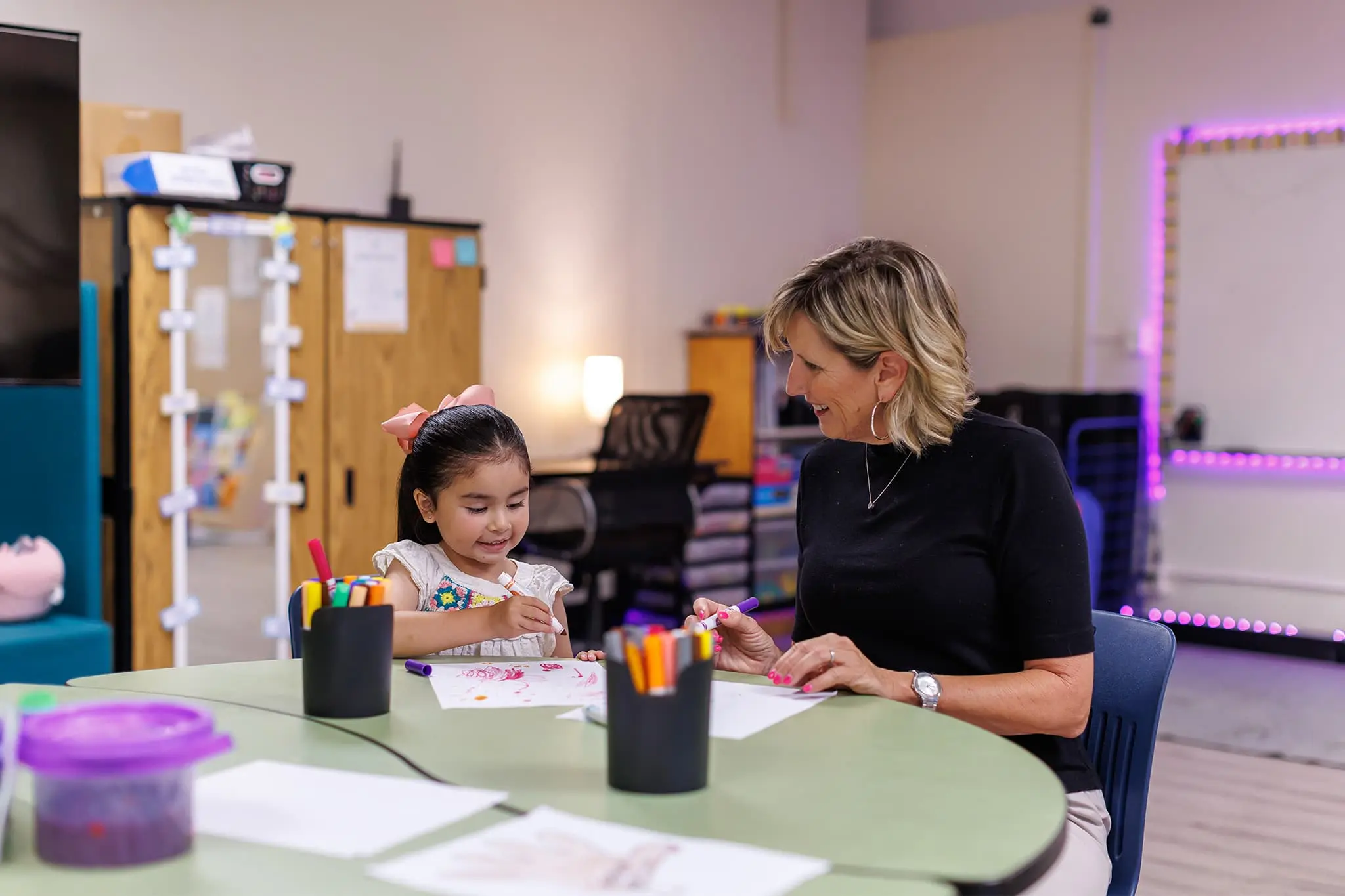 teacher on a table with her student teaching her how to draw