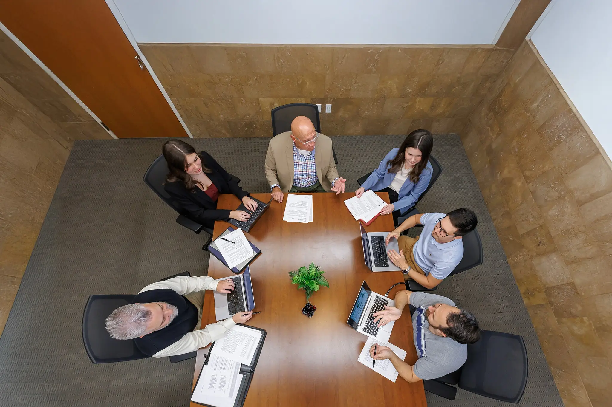 students talking to professor and smiling while holding books.
