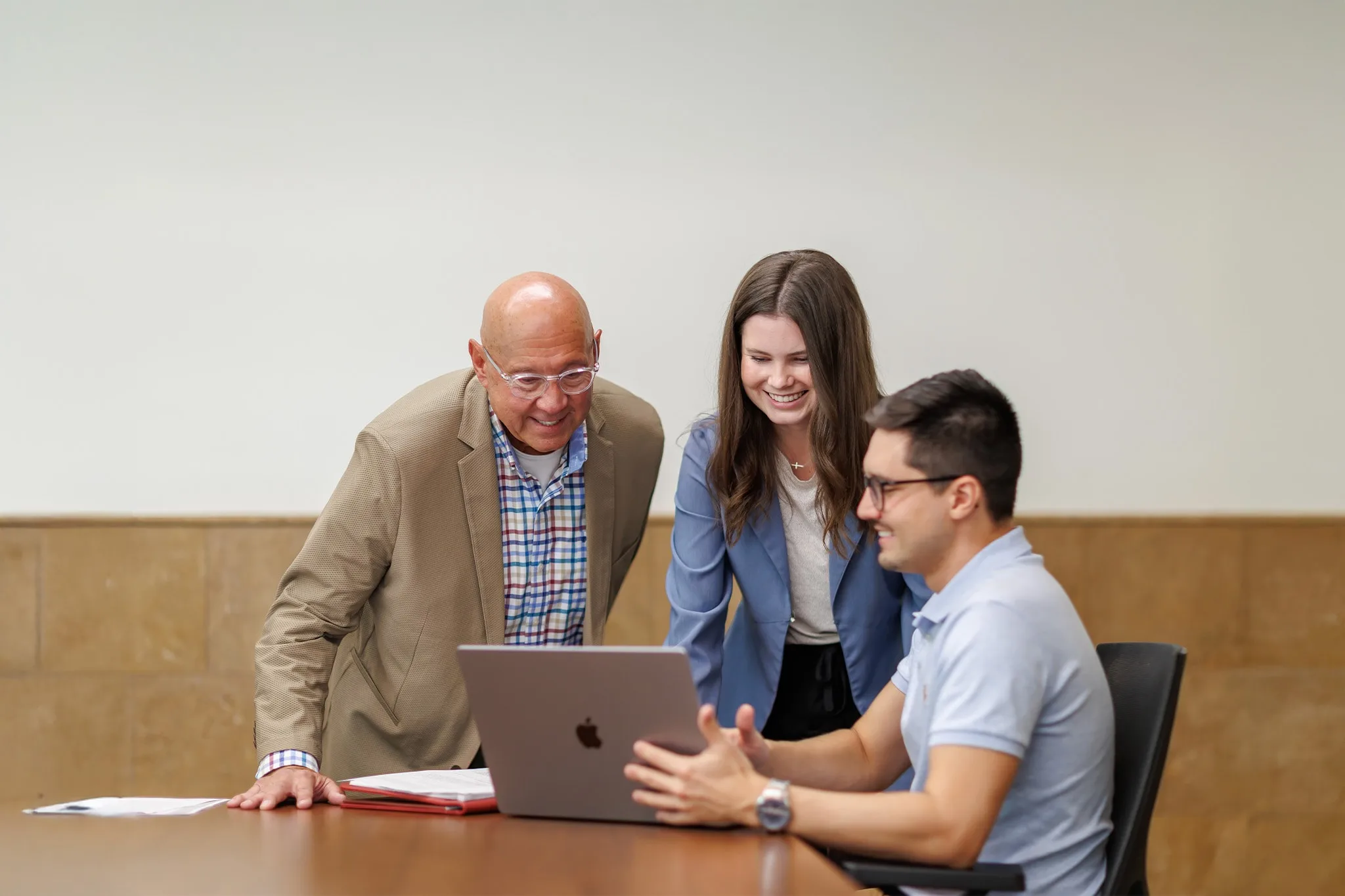 student using their laptop during class showing something to professor and classmate