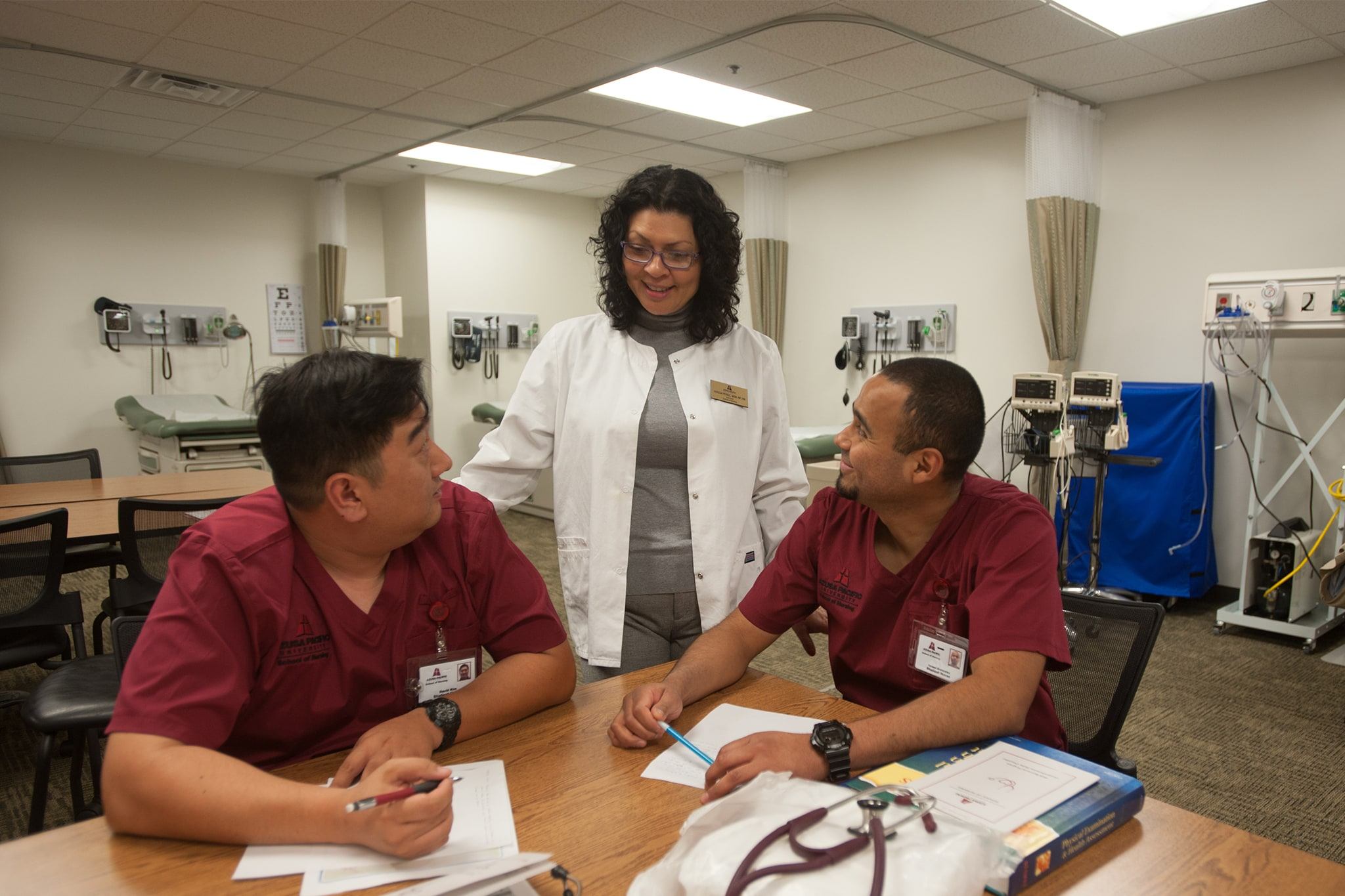 Nurse instructor helping two nursing students