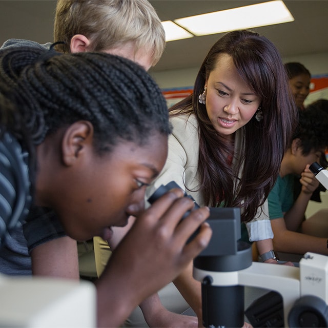 Kim helping students use a microscope