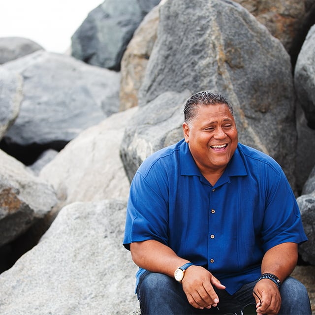Rene smiling while sitting on a rock